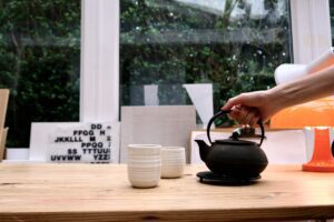 Cast iron teapot and ceramic cups on a wooden table in a light filled home - Rhizo Home