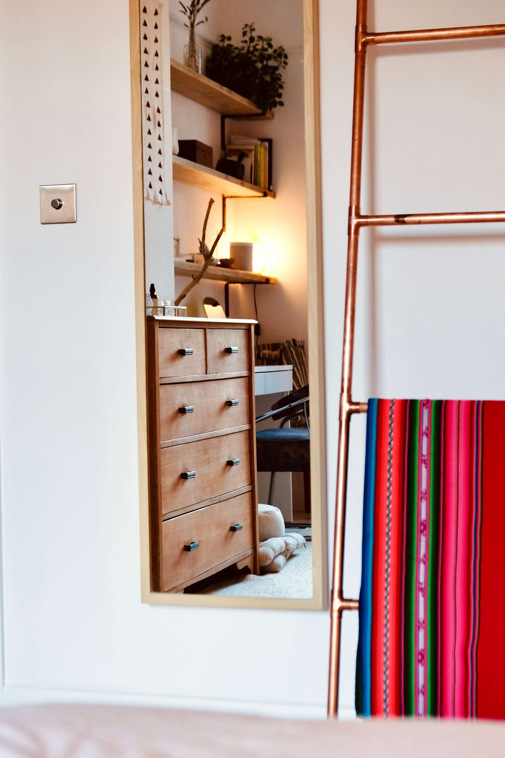 Gold full length mirror and copper ladder with colourful blanket in intentionally styled bedroom - Rhizo Home